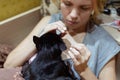 A woman with a white manicure strokes a black cat