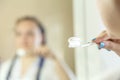 Woman in a white robe with a blue afro hairstyle in the bathroom with a toothbrush in her hands in blur