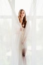 woman in white robe stands on windowsill. morning of bride. reflection in glass Royalty Free Stock Photo
