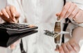 A woman in a white shirt counts coins in a stack on a calculator