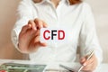 A woman in a white shirt holds a piece of paper with the text CFD, business concept