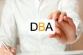 A woman in a white shirt holds a piece of paper with the text: DBA. DBA - doctor of business administration. Business concept