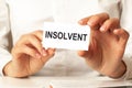 a woman in a white shirt holds a piece of paper with the text: insolvent. business concept