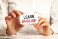 A woman in a white shirt holds a piece of paper with the text: learn english. business concept Royalty Free Stock Photo