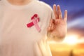 Woman in a white shirt with a pink ribbon and showing an OK sign with a sunset sky background Royalty Free Stock Photo