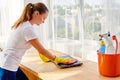 Woman in white shirt and yellow protective rubber gloves cleaning at home and wiping dust with pink rag on laptop computer. Royalty Free Stock Photo