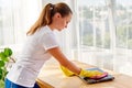 Woman in white shirt and yellow protective rubber gloves cleaning at home and wiping dust with pink rag on laptop computer. Royalty Free Stock Photo