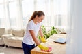 Woman in white shirt and yellow protective rubber gloves cleaning at home and wiping dust on wooden tablel with pink rag. Royalty Free Stock Photo