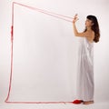Woman white silk nightie making frame with red thread looking at her hand on white background
