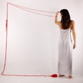 Woman white silk nightie making frame with red threadseen from her back on white background