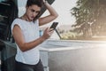 Woman in white sports clothes are standing on city street, relax after sports training, use smartphone, listen to music. Royalty Free Stock Photo