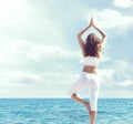 Woman in white sportswear doing yoga on a wooden pier. Sea and Royalty Free Stock Photo