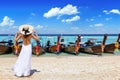 A woman in a white summer dress standing on a beautiful beach in front of longtail boats Royalty Free Stock Photo