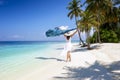 A woman in white summer dress walks on a tropical paradise beach with palm trees Royalty Free Stock Photo