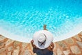 A woman with white sunhat relaxes at the swimming pool