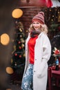 Woman in white sute red pullover smiling in new year decoration near home