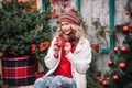 Woman in white sute red pullover stay and smiling in new year decoration near home with drink tea with red cup