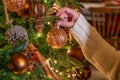 Woman hangs glass bauble on Christmas tree