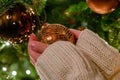 Woman hangs glass bauble on Christmas tree