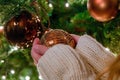 Woman hangs glass bauble on Christmas tree