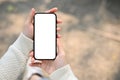 A woman holding a smartphone white screen mockup over blurred street in background Royalty Free Stock Photo