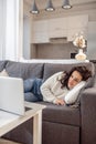 A woman in white sweater lying on the sofa and watching something online Royalty Free Stock Photo