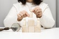 A woman in a white sweater puts a wooden figurine on the podium. The concept of employee search, career advancement. Talented