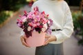 Woman holding a huge pink box of different rose color flowers