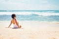 Woman in white swimsuit sits on empty ocean beach in sunny day Royalty Free Stock Photo