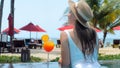 Woman in white swimwear and hat relax in swimming pool enjoy beautiful sea view with sun beds at sandy beach with Royalty Free Stock Photo