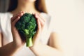 Woman in white T-shirt holding broccoli in hands. Copy space. Healthy clean detox eating concept. Vegetarian, vegan, raw