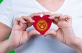 Woman in white t-shirt holds a heart in the form flag Kyrgyzstan on her chest.