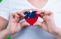 Woman in white t-shirt holds a heart in the form flag Samoa on her chest.