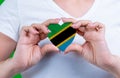 Woman in white t-shirt holds a heart in the form flag Tanzania on her chest.