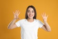 Woman in white t-shirt showing number nine with her hands on yellow background Royalty Free Stock Photo