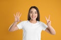 Woman in white t-shirt showing number seven with her hands on yellow background Royalty Free Stock Photo