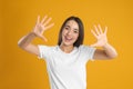 Woman in white t-shirt showing number ten with her hands on yellow background Royalty Free Stock Photo