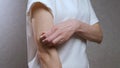 A woman in a white T-shirt strongly combs her hand with her nails. Scabies, eczema, giardia