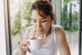 Woman in white tank top is drinking hot drink in the cup. Royalty Free Stock Photo