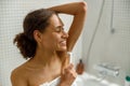 Woman in white towel shaving her armpits with razor. Depilatory procedure at bathroom