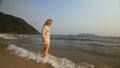 Woman in a white tunic on the beach, near the stormy sea. Blonde Royalty Free Stock Photo