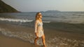 Woman in a white tunic on the beach, near the stormy sea. Blonde Royalty Free Stock Photo