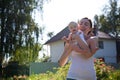 Woman holding baby on arms against a house Royalty Free Stock Photo