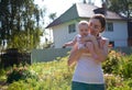 Woman in white vest holding baby on arms outdoors Royalty Free Stock Photo