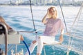 Woman on white yacht in nautical theme in open sea. Blond hair and blue clothes.