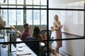 Woman at whiteboard in team meeting, seen through glass wall Royalty Free Stock Photo