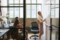 Woman at whiteboard in team meeting, seen through open door Royalty Free Stock Photo