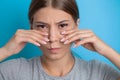 Woman who suffers from a terrible pain in her teeth, touching her cheeks with her hand palm.