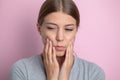 Woman who suffers from a terrible pain in her teeth, touching her cheeks with her hand palm.