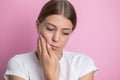 Woman who suffers from a terrible pain in her teeth, touching her cheeks with her hand palm.